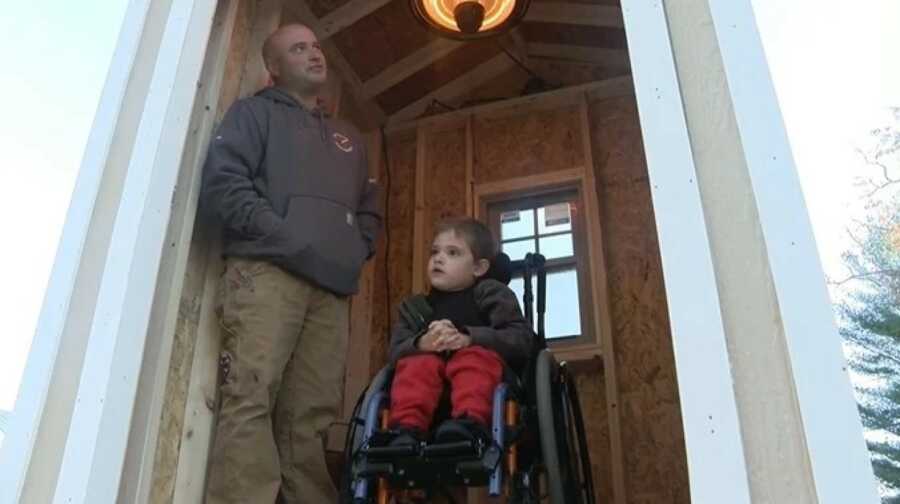 father and son sit in shelter built for them at bus stop