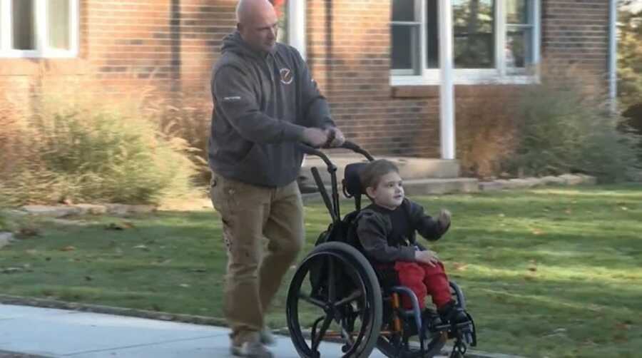 father pushing son towards bus stop 