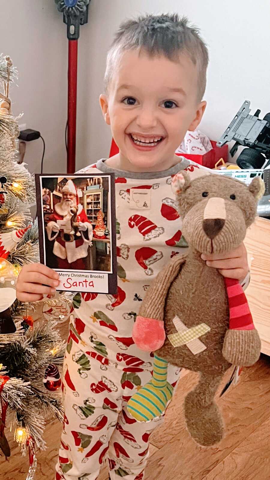 Boy thrilled to receive a teddy bear with a letter and a picture from Santa as a Christmas gift
