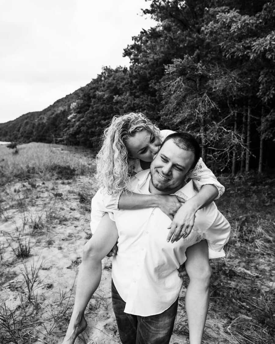 wife on husbands back kissing his head as they take a picture