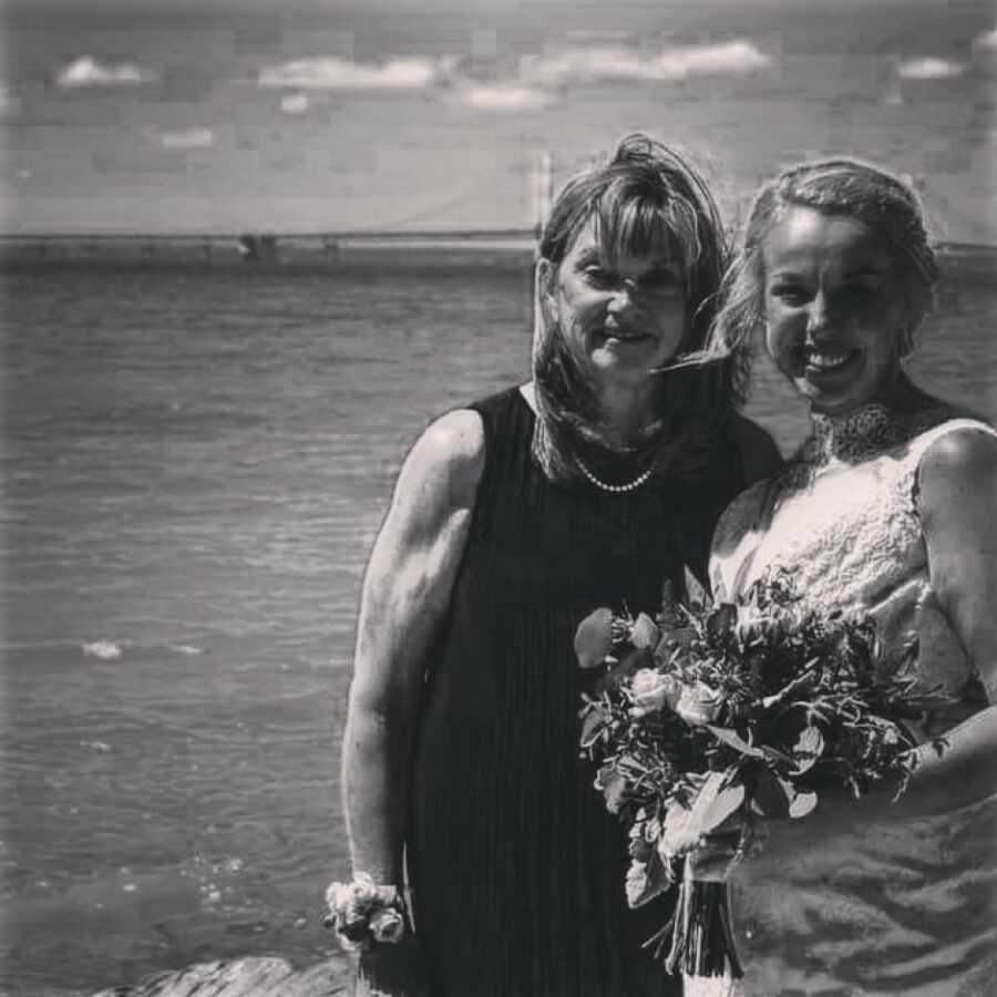 mother in law and daughter in law on wedding day posing by the water