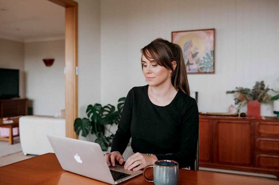 woman sitting at a table with a laptop open in front of her