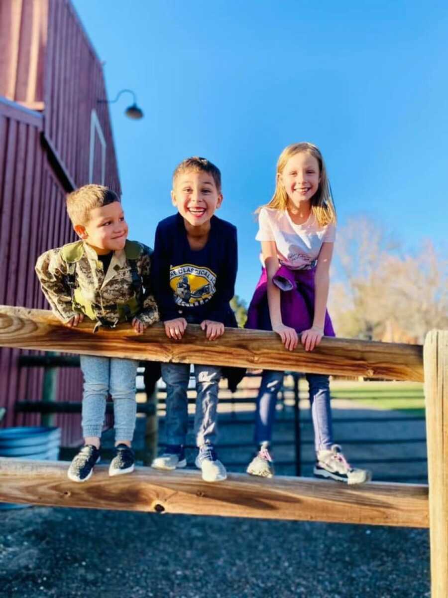 three kids standing on a ledge, one with ADHD, but smiling and playing 