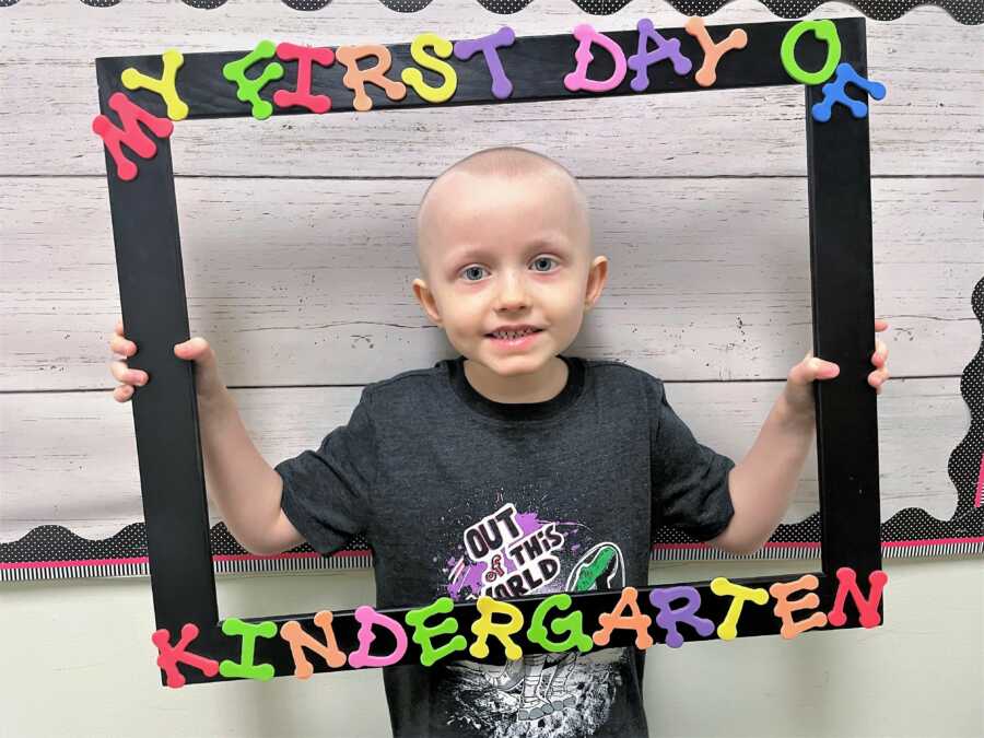 5-year-old kid diagnosed with Wilms Tumor holding a big frame that says my first day of Kindergarten 