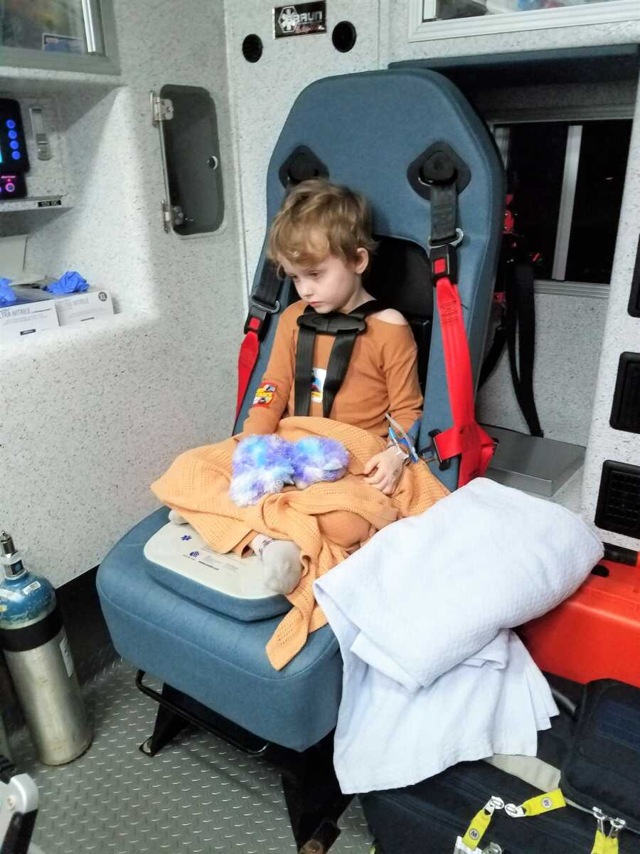 5-year-old kid diagnosed with Wilms Tumor receiving treatment, sitting in a chair with a blanket on his legs and a stuffed animal