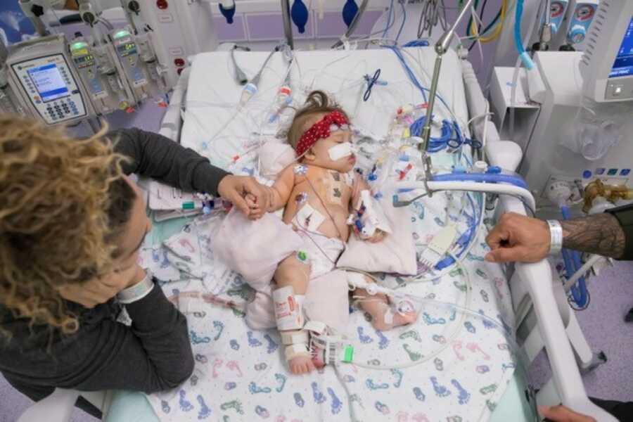 mom holding baby girl's hand while she is recovering