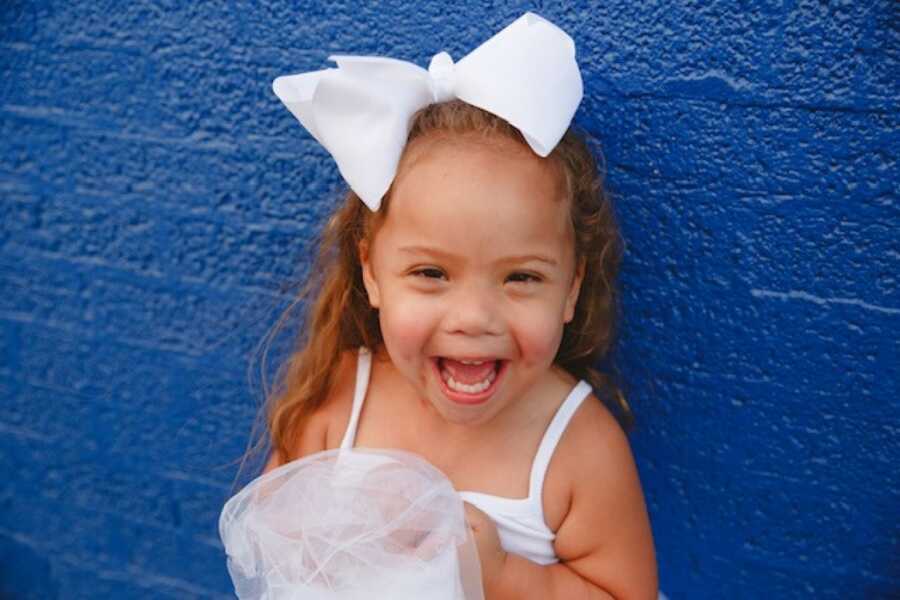 little girl wearing a white bow on a blue wall