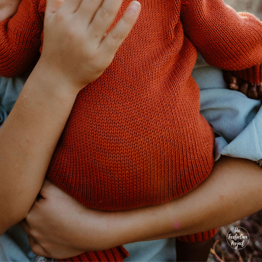 baby in orange being held by his mom