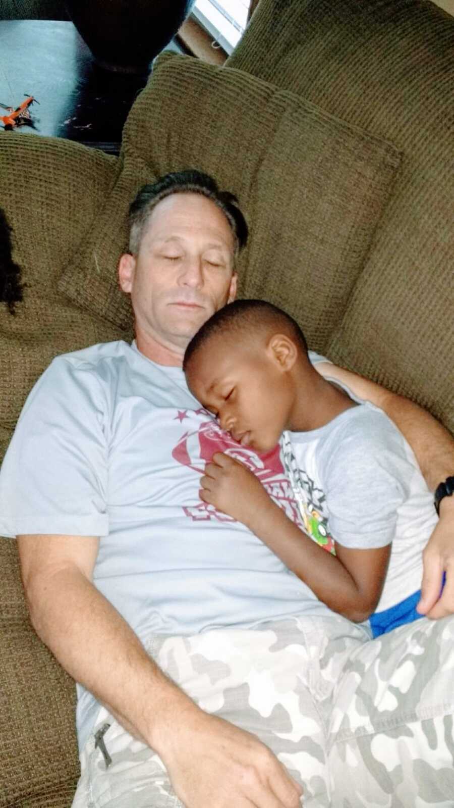 Adoptive dad naps on the couch with one of his adoptive sons