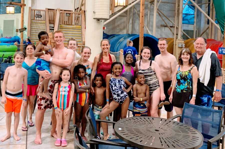 Woman takes a photo with her children and her extended family while enjoying a pool day together