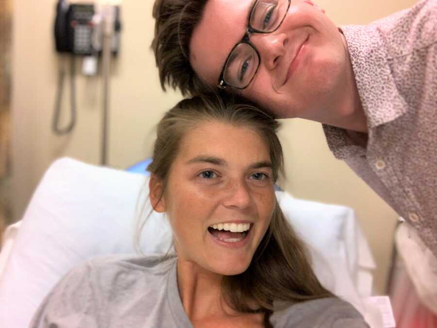 Young woman battling chronic pain takes a funny selfie with her husband while at the hospital