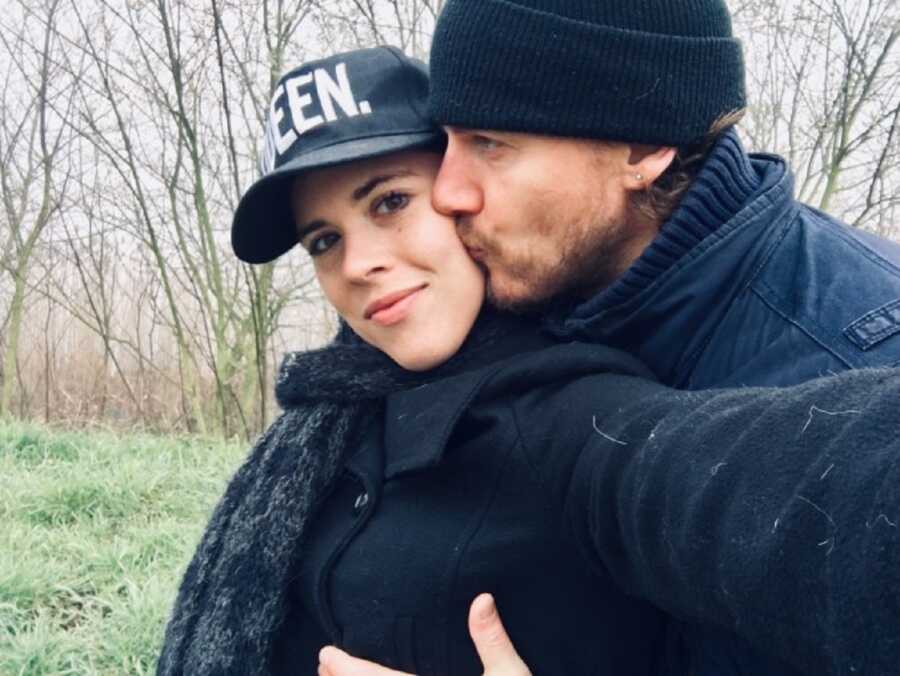 American Girl and Dutch man kiss on the cheek. woman wears hat saying QUEEN