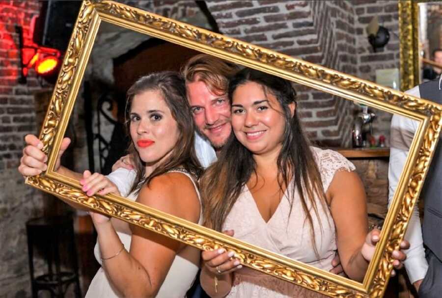 friends celebrating at a wedding party holding a golden frame