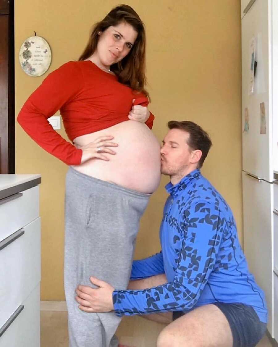 Husband kisses his wife's pregnant belly 