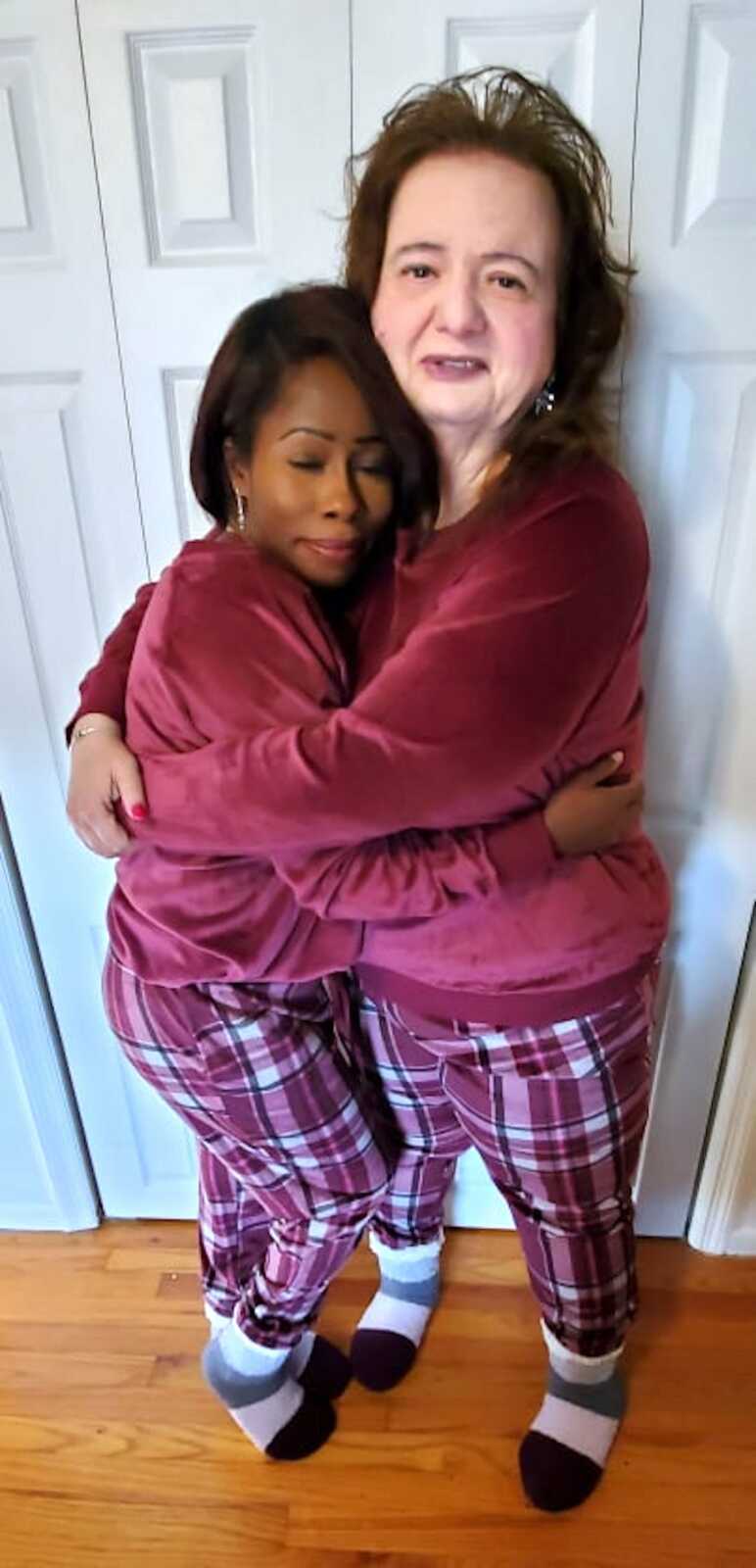Adoptive mother and daughter wearing matching pajamas and embracing.