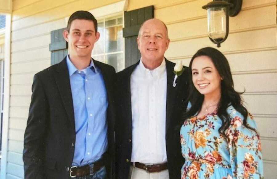 Dad takes a photo with his two kids at a wedding