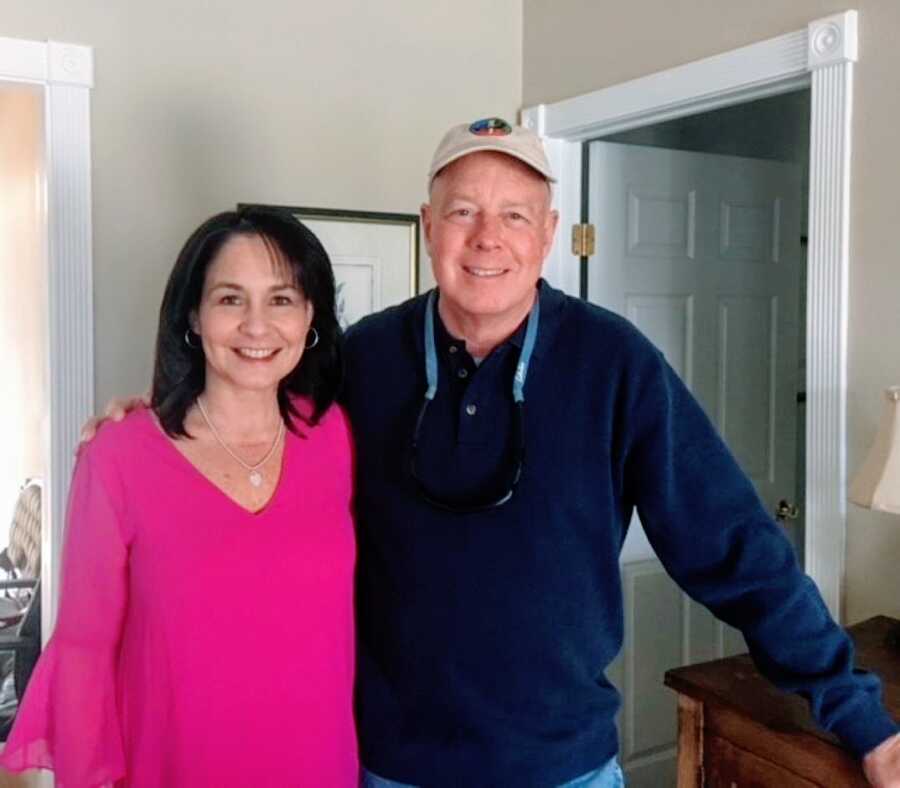 Husband and wife smile for a photo together before taking family pictures