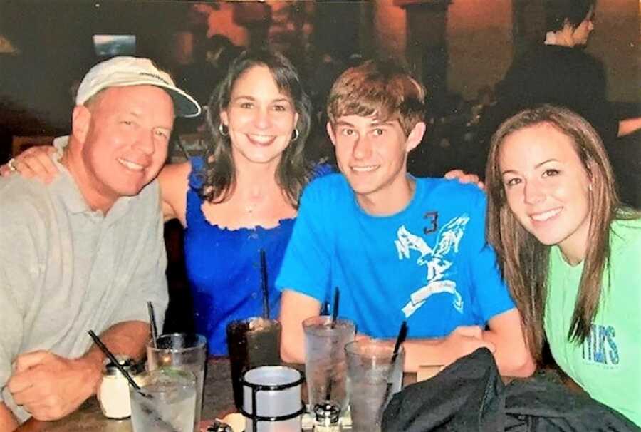 Happy family eating at a restaurant with drinks on the table and smiling at the camera