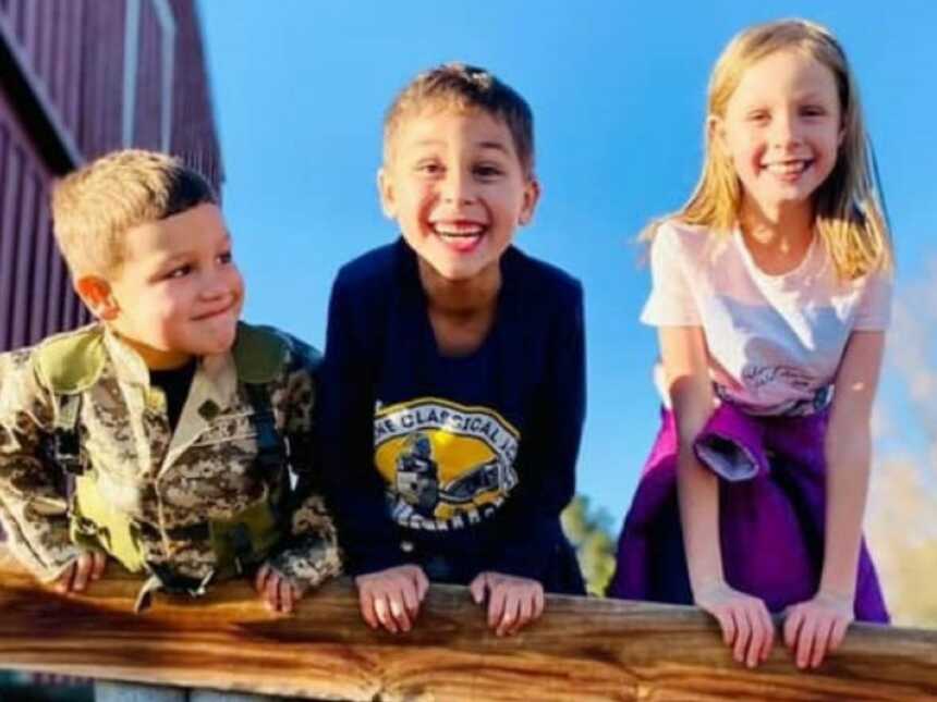 three kids standing on a ledge, one with ADHD, but smiling and playing