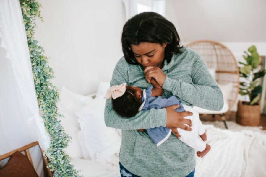 mom holding her new born daughter kissing her hand