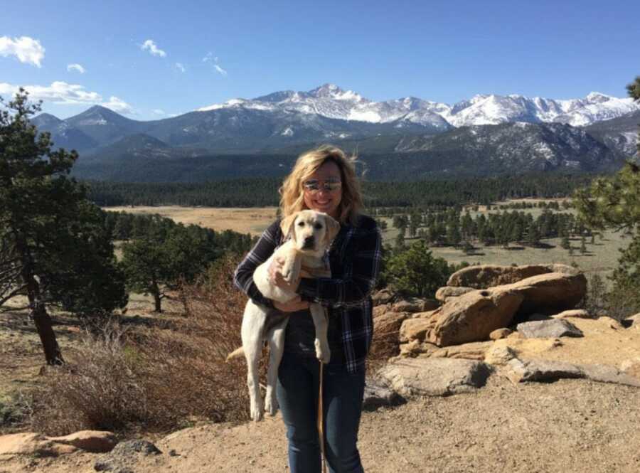 woman holding her dog on a hike