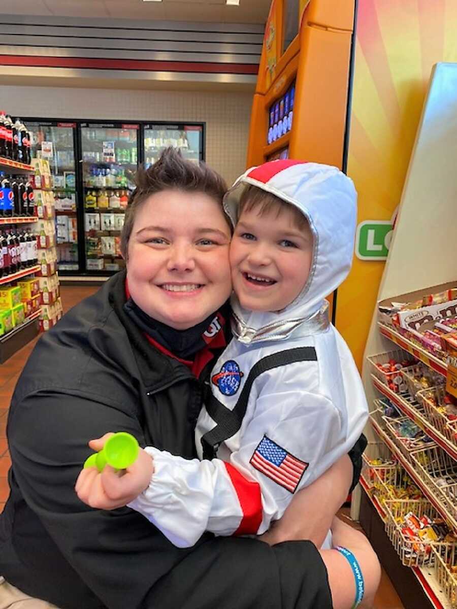 LGBT mom hugging her autistic son who is wearing an astronaut costume inside of a convenience store 