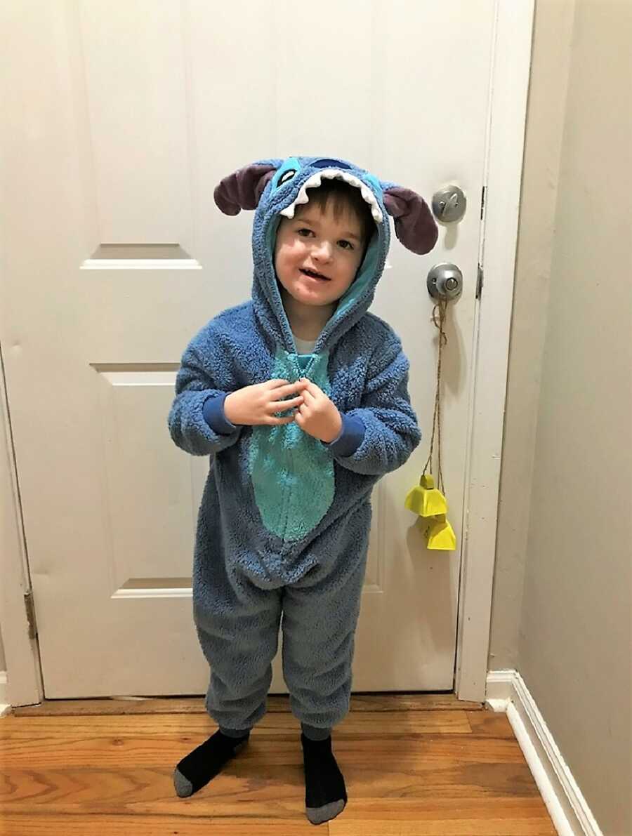 autistic boy in a Stitch onesie pajamas in front of bedroom door 