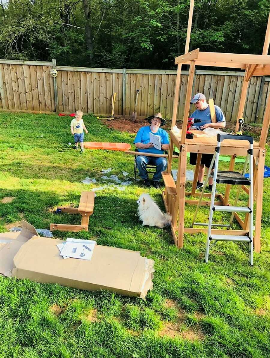 autistic kid playing in the backyard while mom and grandfather work on home improvements 