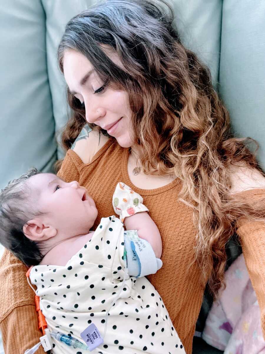 Mom looks down at newborn daughter as they share a sweet smile together