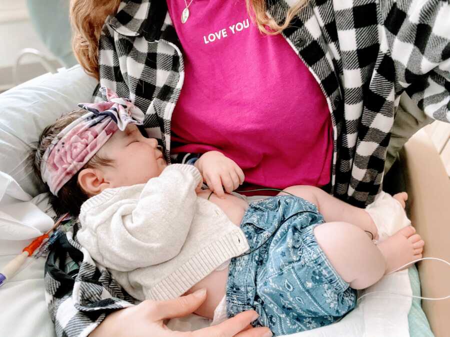 Mom holds daughter in her lap while she smiles in her sleep