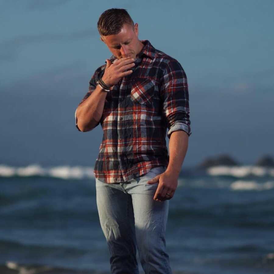 man looking down in front of water scene