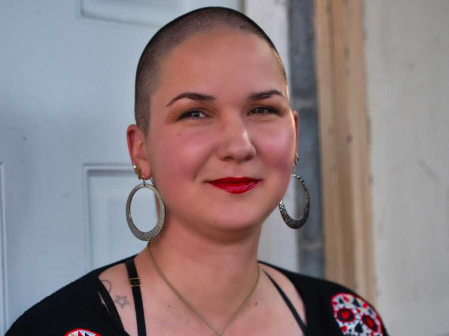woman with a shaved head smiling for the camera