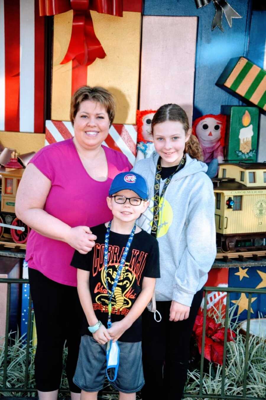 Mom takes a photo with her two children while at a theme park
