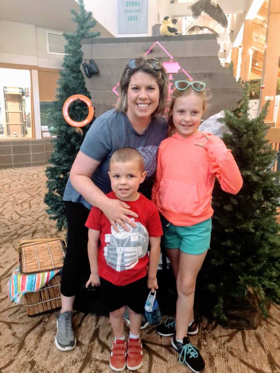 Mom and children take a group photo in front of Christmas trees