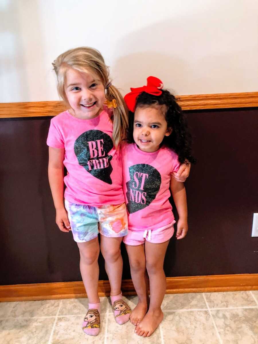 Two sisters wear matching pink shirts that say "best friends"