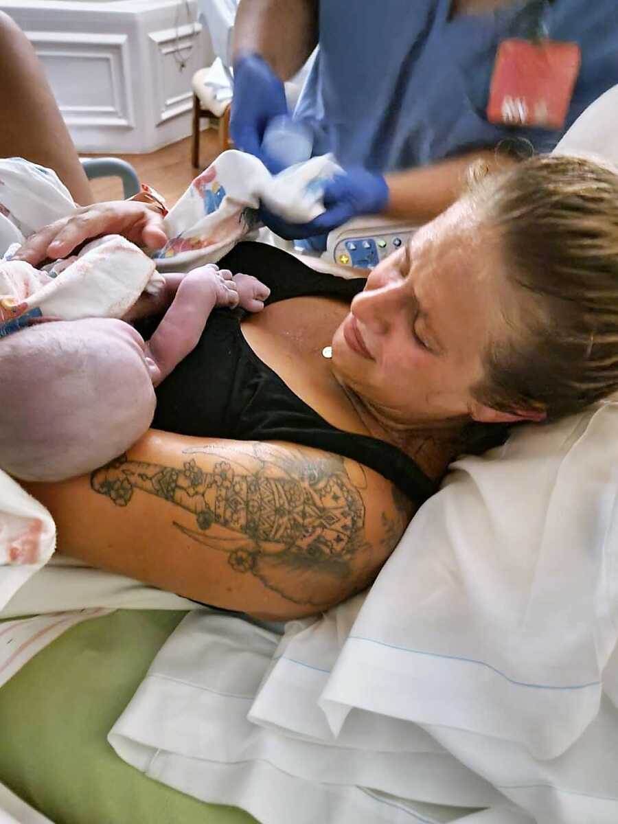 mother holding newborn rainbow baby girl for the first time after childbirth, after battling with infertility. 