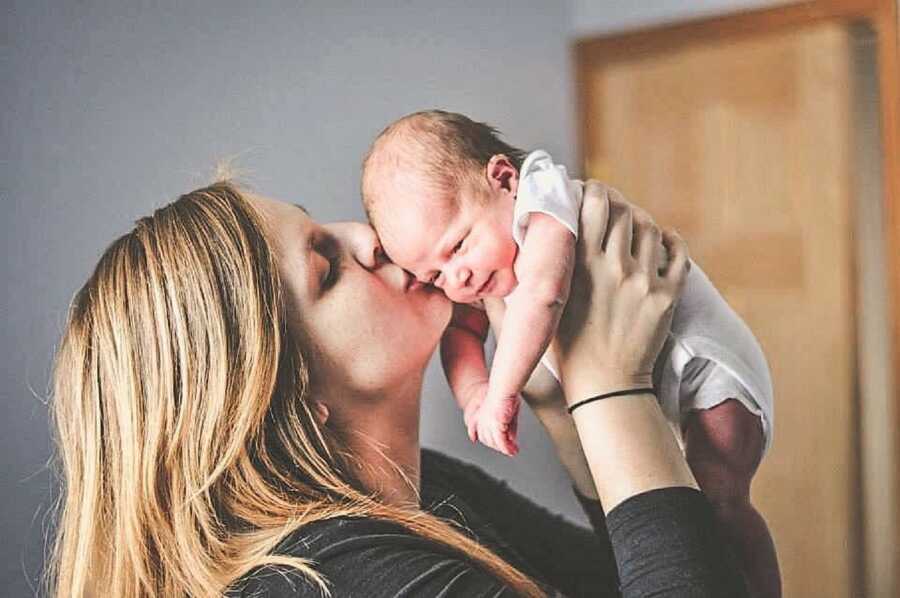 Mom kisses newborn son on the cheek