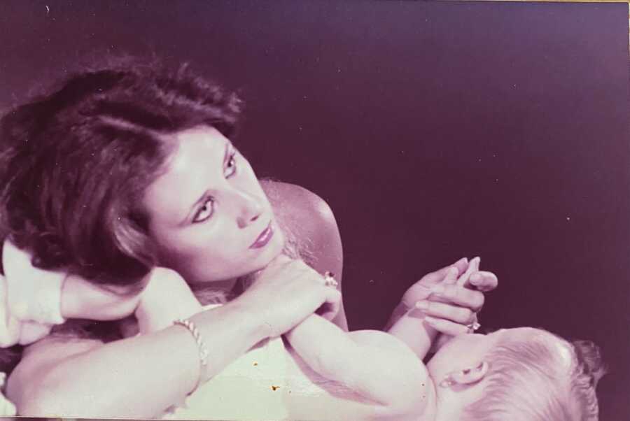 mother holding baby daughter's hand while looking at the horizon