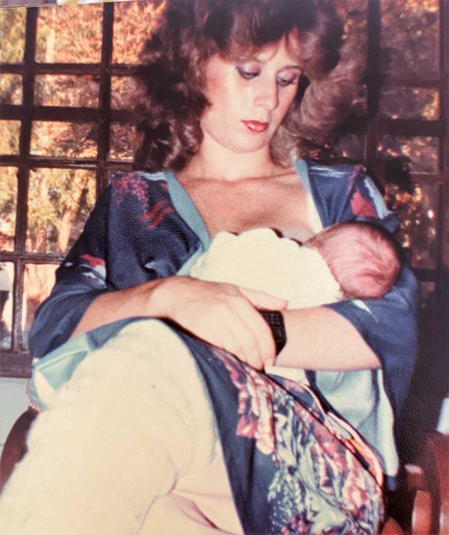 Mother breastfeeding baby daughter while wearing a blue-print robe