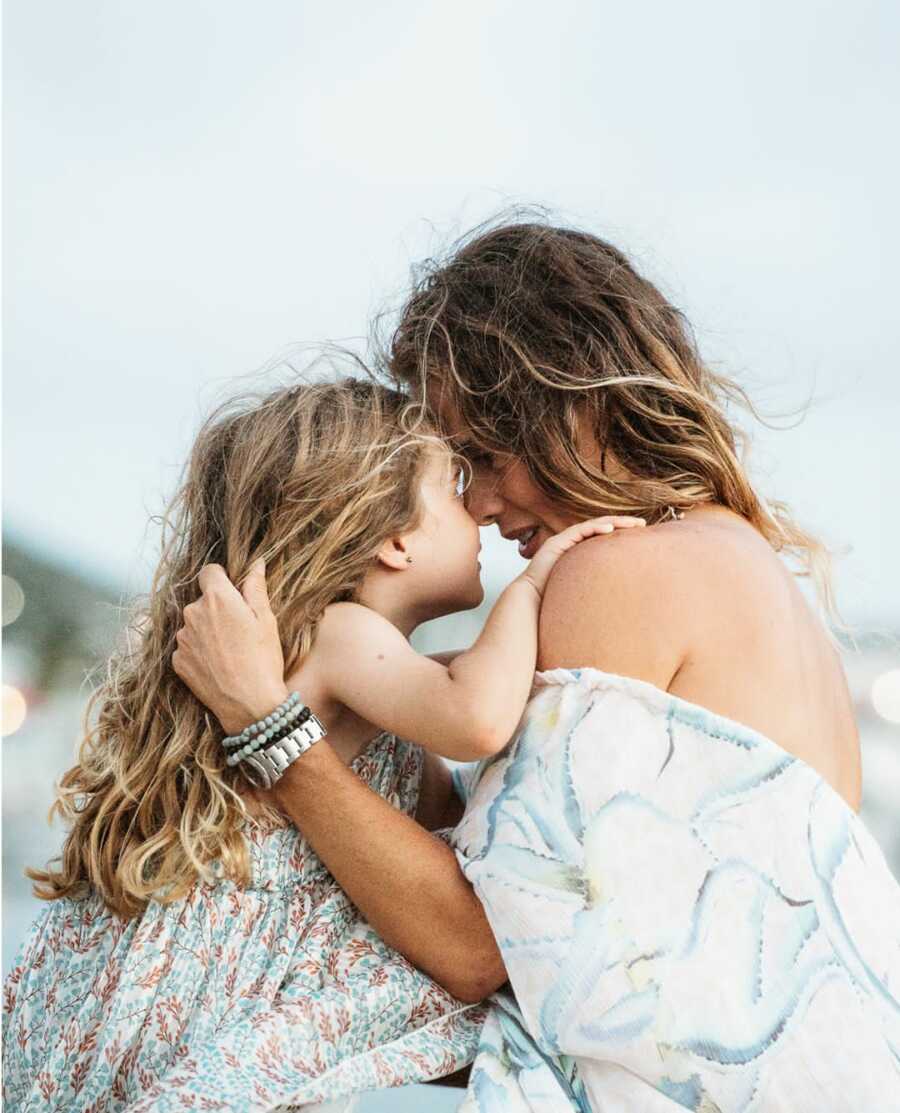 mother and daughter closely staring at each other wearing print dresses 