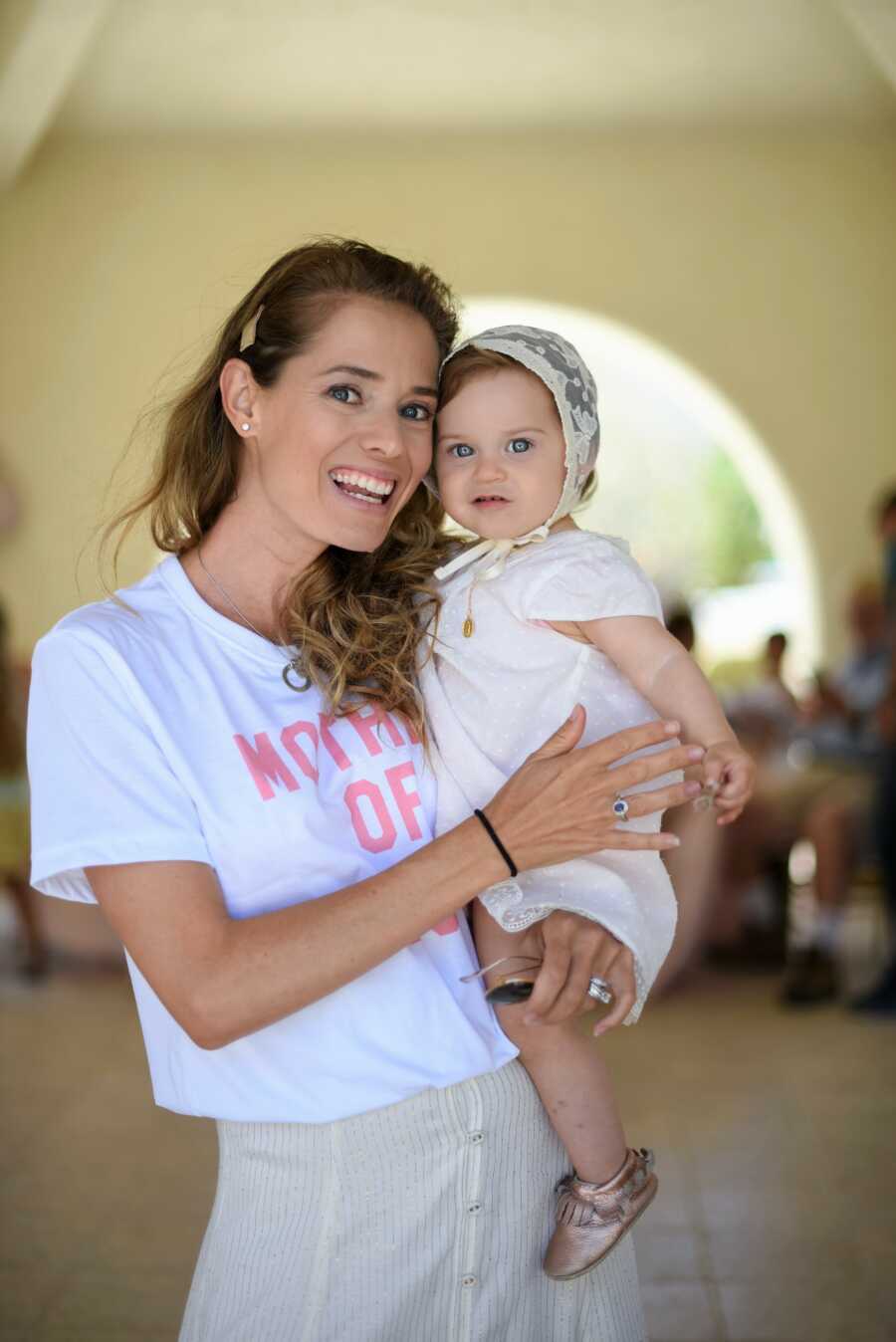 mother holding baby daughter at her first communion 