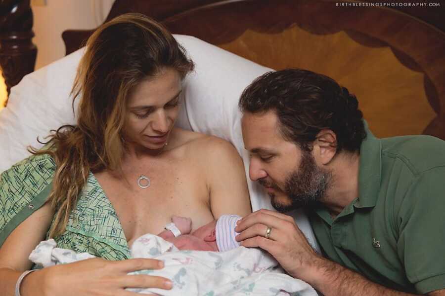 mother and father stare at newborn baby girl right after childbirth 