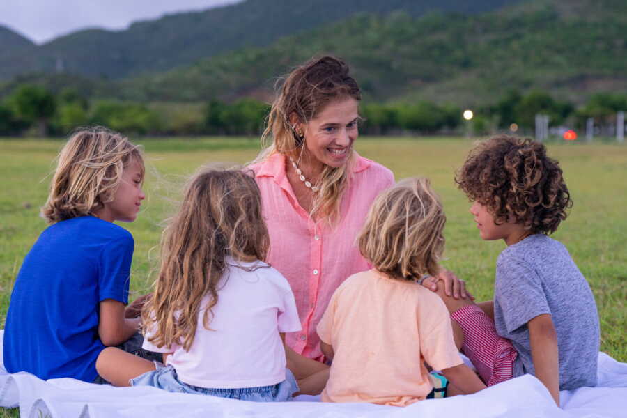 mother sits in a circle with her four kids and have a happy conversation 