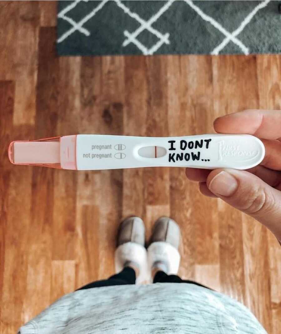 Woman struggling with infertility takes a photo of a negative pregnancy test with 'I don't know' written on it