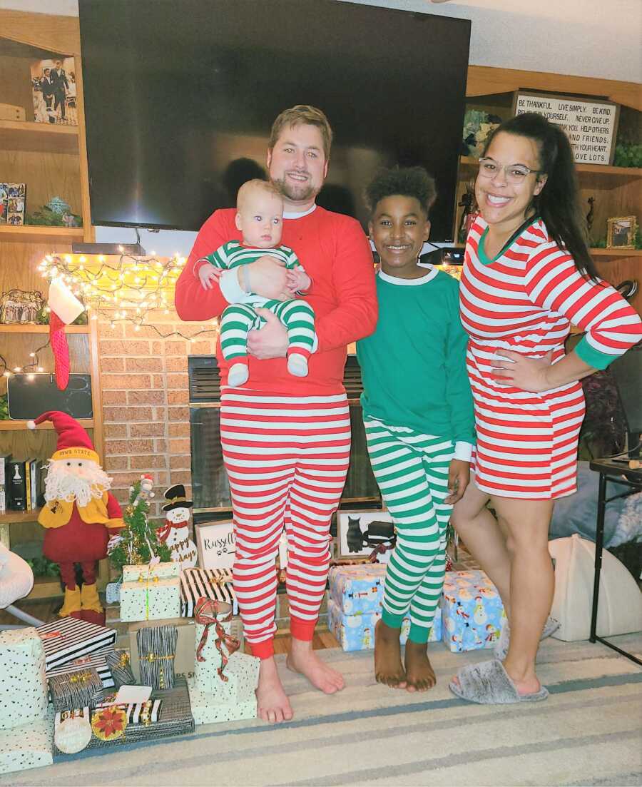 Blended family of four take a photo together on Christmas in matching red and green pajamas