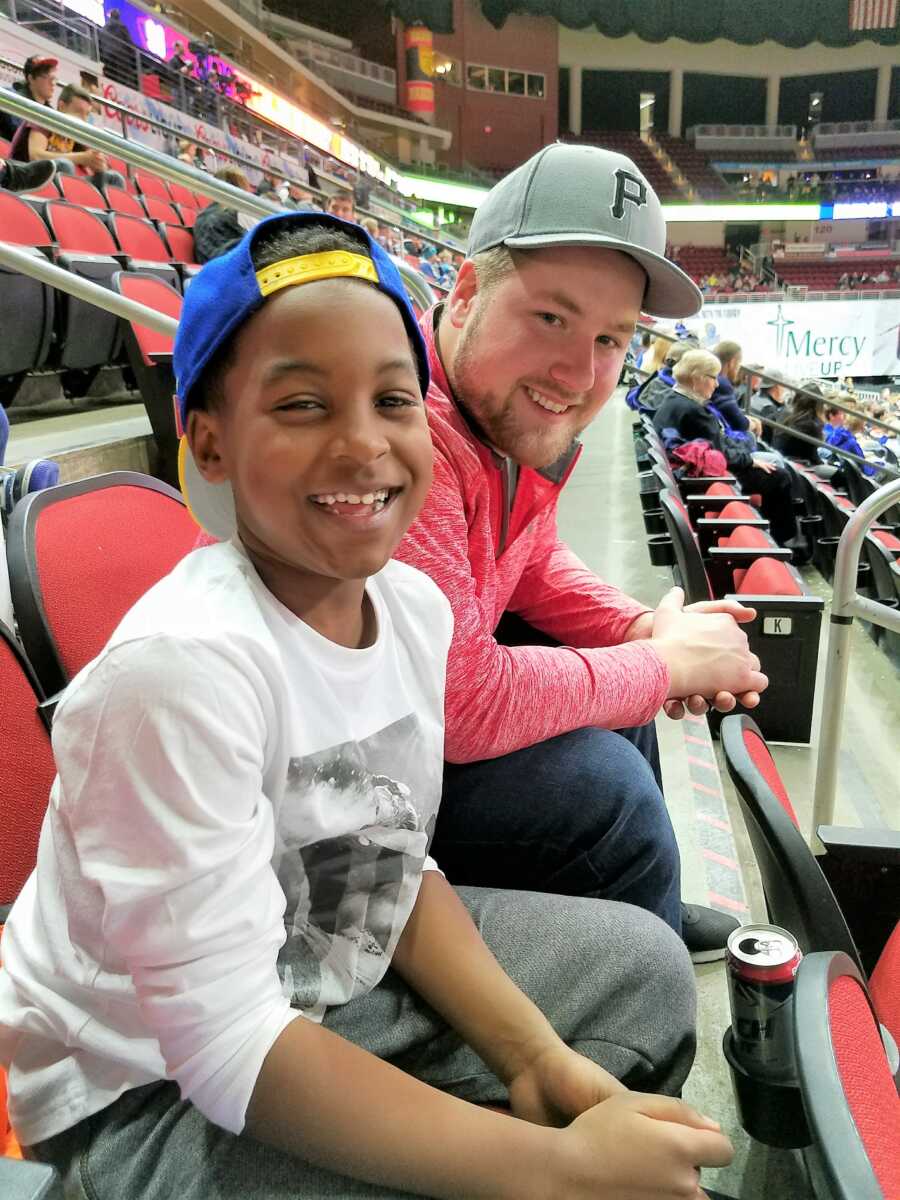 Teen mom takes a photo of her son and boyfriend having fun together at a basketball game