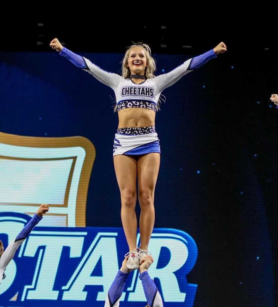 cheerleader being held up by another teammate