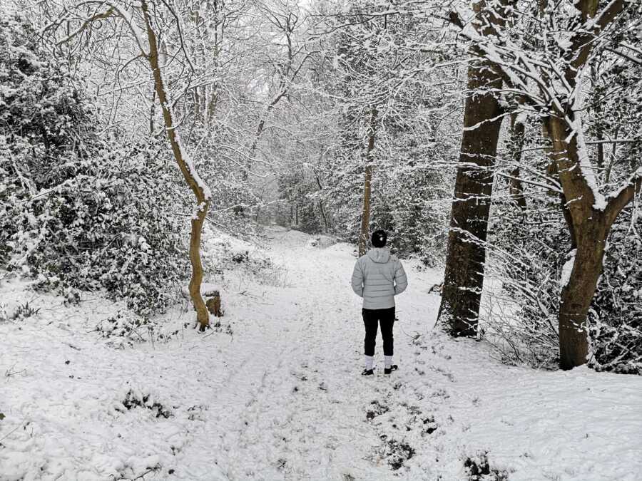 man standing in the woods after it had snowed