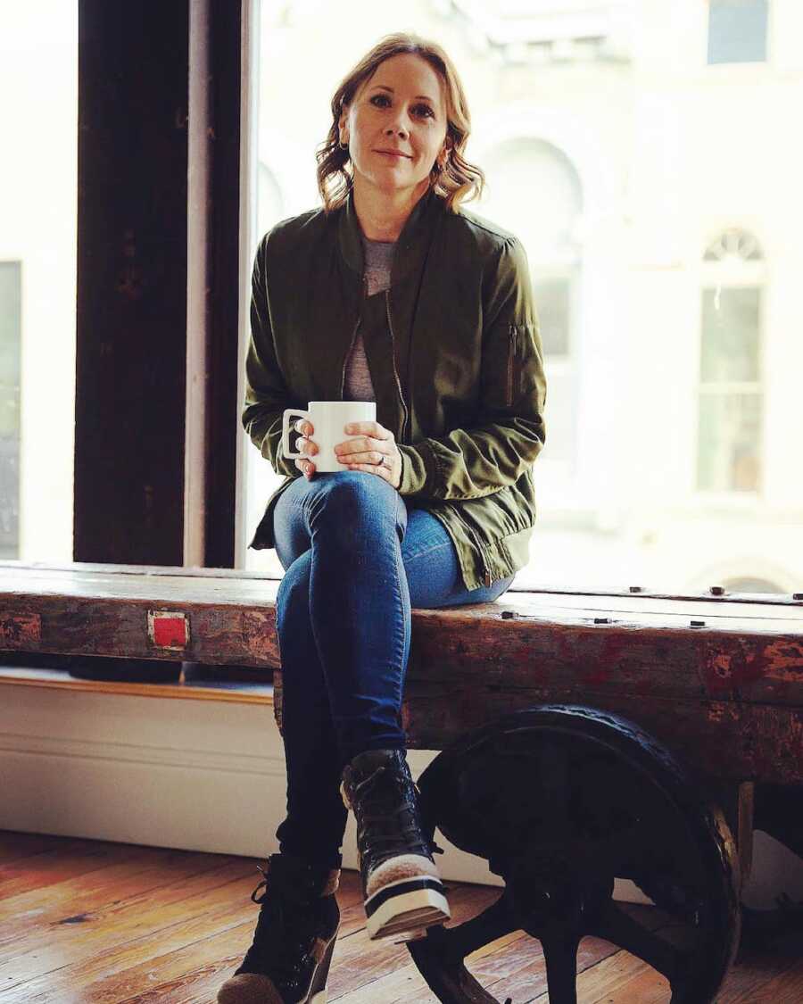 woman holding a cup of coffee on a bench