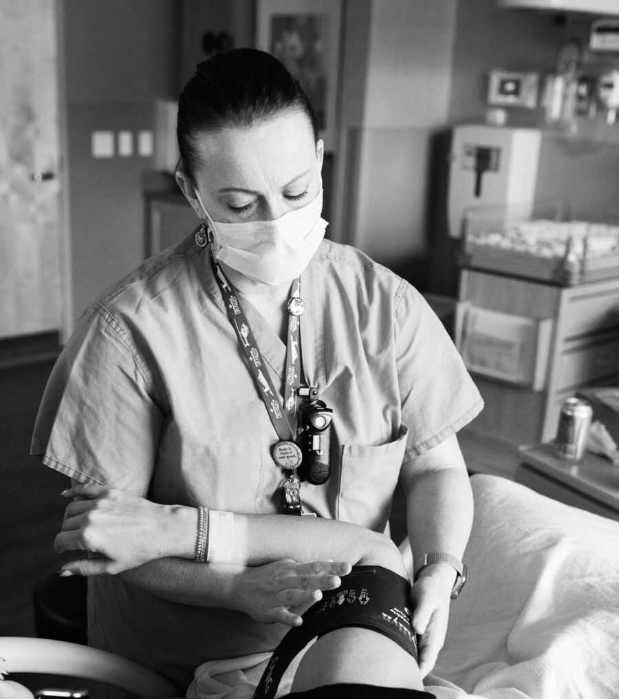 nurse stands over a mother who is delivering a stillborn baby, the nurse offers her support
